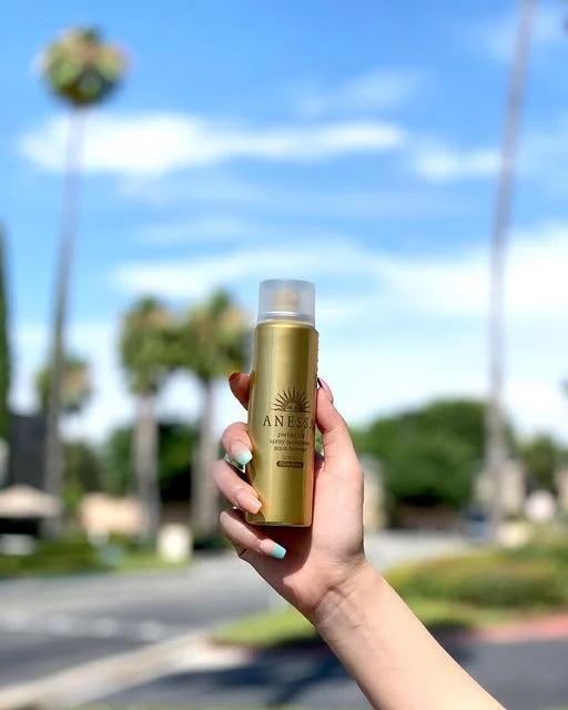 Anessa sunscreen held outdoors beneath palm trees