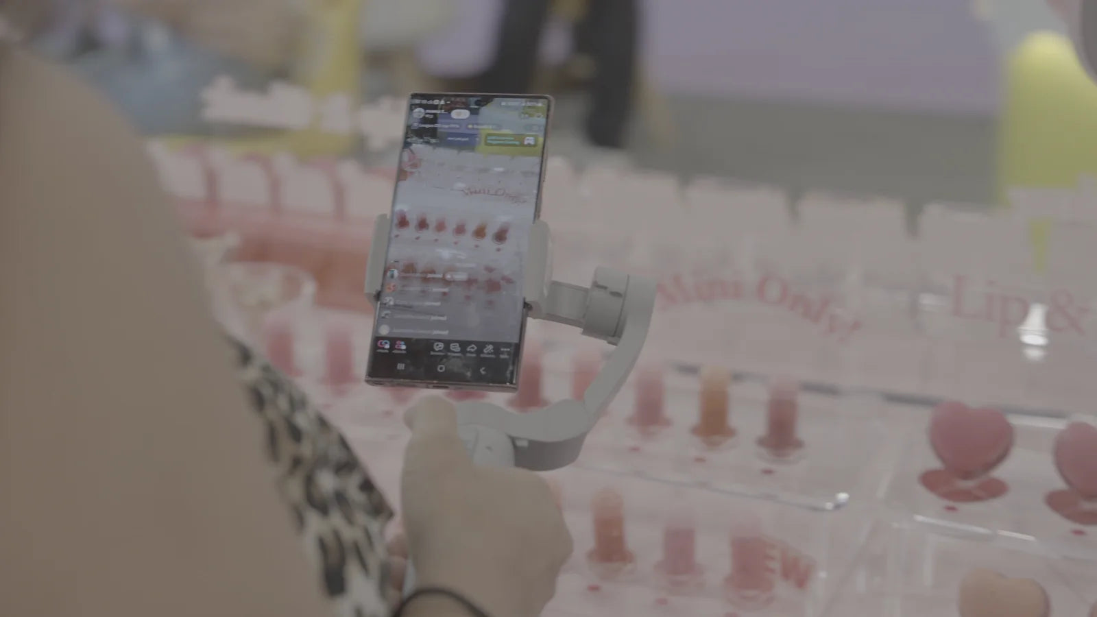 A smartphone on a stabilizer filming a beauty product display