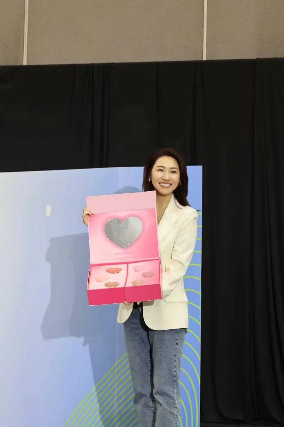 A product moment beside the event backdrop, with a heart-shaped detail at the center.